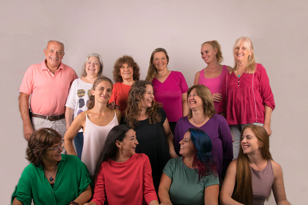 Mujeres y un hombre posando todas juntas mirando la cámara sonriendo