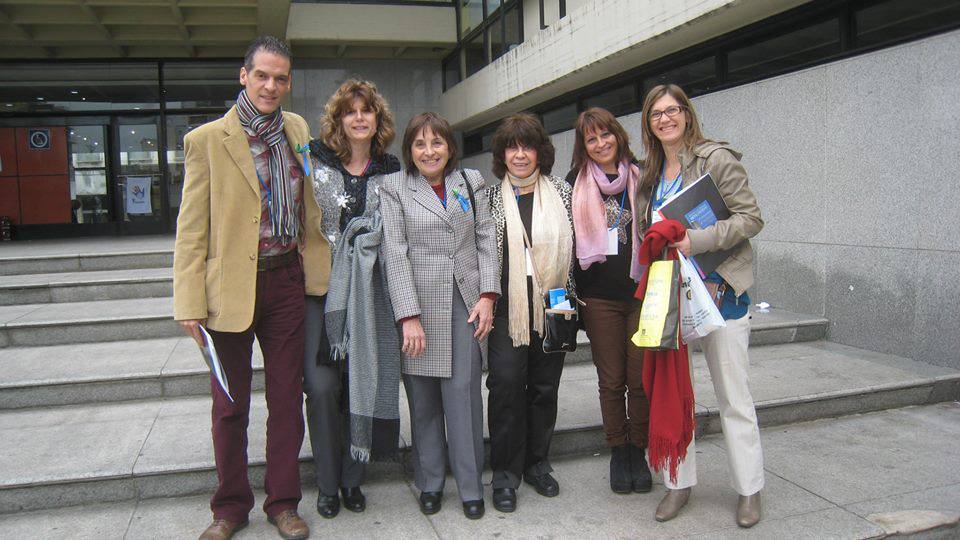 Seis personas en el ingreso a un edificio al aire libre sonríen a la cámara