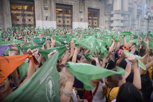 Mujeres levantando el pañuelo verde de lucha por el aborto legal, seguro y gratuito en las calles